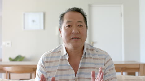 senior man talking and gesturing while sitting in living room at home
