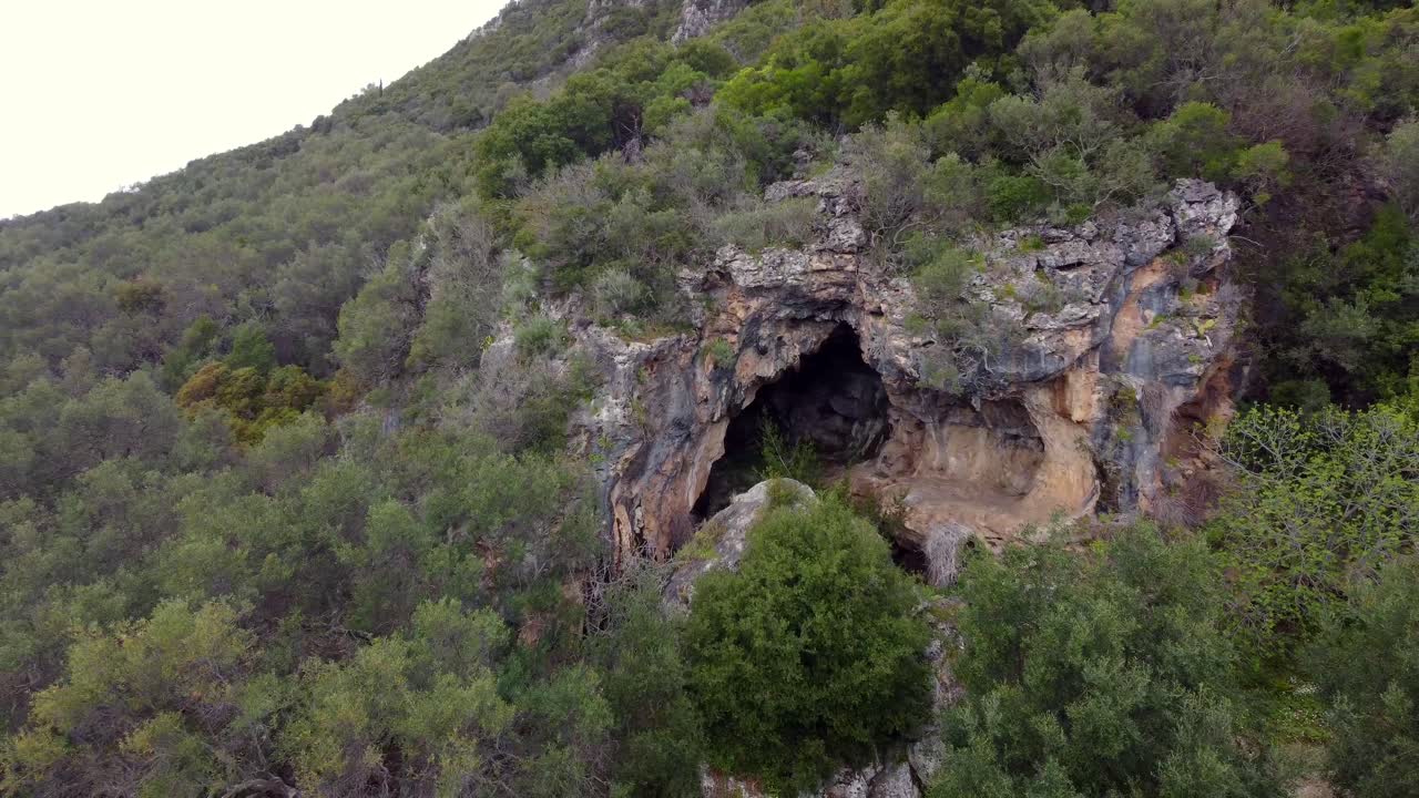 increíble vista aérea larga vuelo volar hacia atrás imágenes de drones de una gran cueva en una montaña en la naturaleza salvaje corfú esperar al explorador en grecia 4k vista cinematográfica desde arriba por philipp marnitz primavera de 2022