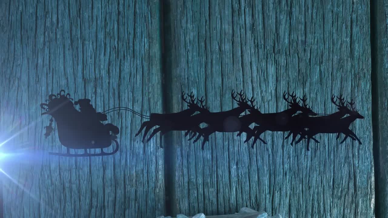 Animation of light trails and santa claus in sleigh with reindeer over wooden background