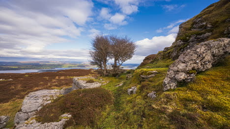 panorama motion timelapse de paisaje rural con rocas, árboles y ovejas en un campo pantanoso y colinas y lago en la distancia durante un día nublado soleado visto desde carrowkeel en el condado de sligo en irlanda
