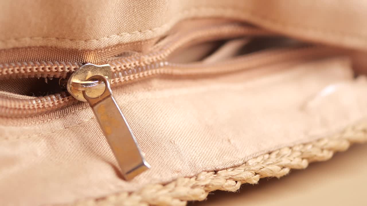 Primo piano di una borsa in tessuto beige con una cerniera aperta