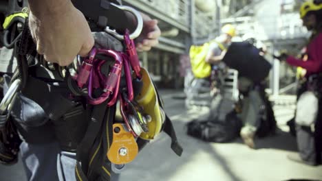 a climbing crew adjusts their harnesses and safety gear before climbing an industrial building