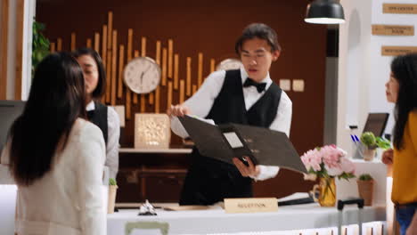 남자 리셉션 담당자가 레지스트리에서 손님 예약을 검색하고 있습니다.