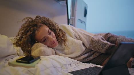 camp tourist looking laptop lying trailer bed at evening close up. woman sleepy