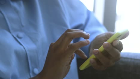 person is using smartphone, scrolling and typing on touch screen, at home on the sofa