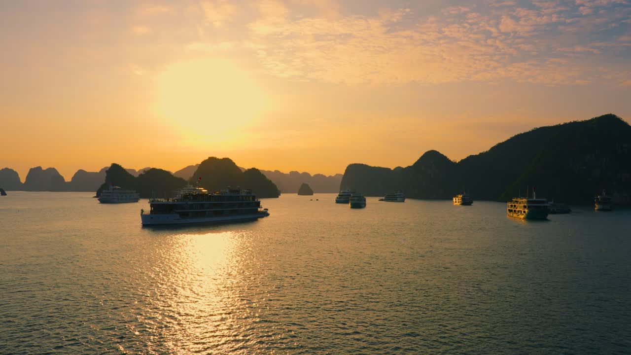 Many Cruise ships anchored at Halong Bay back lit with rising sun, Vietnam
