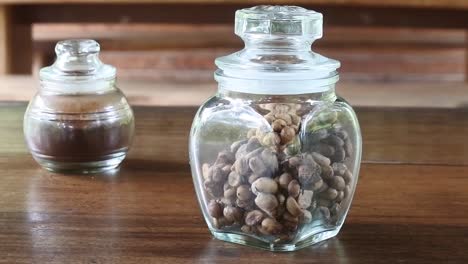 Pan-shot-of-authentic-Indonesian-luwak-coffee-in-a-glass-jar-on-a-wooden-table