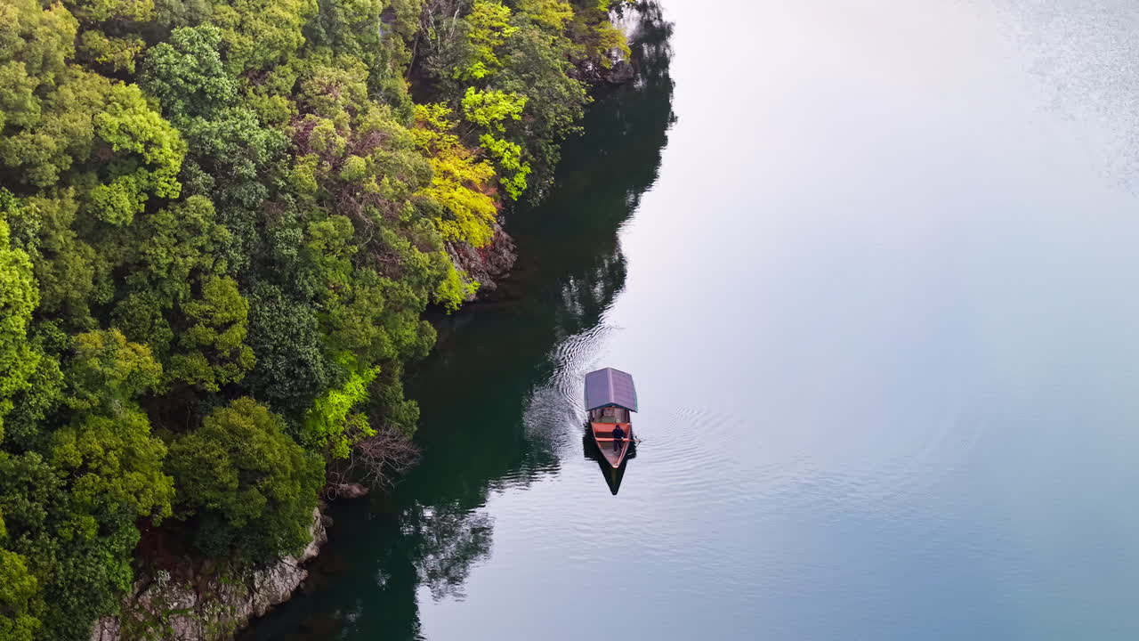 Aerial drone view of a boat moving on the Katsura River in Arashiyama, Japan in daylight