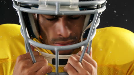 wearing yellow jersey, football player adjusting helmet with focused expression