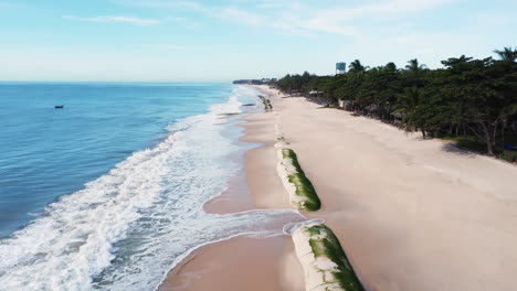 Aerial-flying-over-geotubes-on-beach-being-destroyed-by-sea-currents,-Vietnam