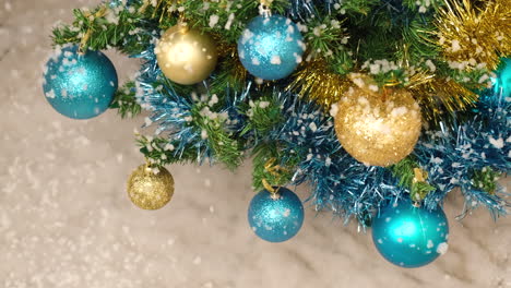 snow falling on christmas tree with golden balls