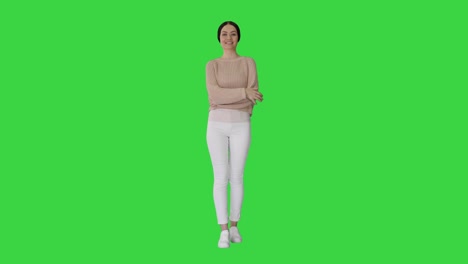 young smiling woman waving her hand as a greeting looking to the side on a green screen, chroma key