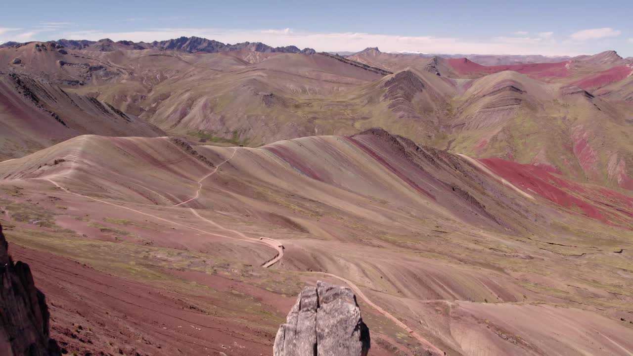 formaciones rocosas escarpadas se elevan sobre una colorida cordillera en perú, bajo un cielo despejado.