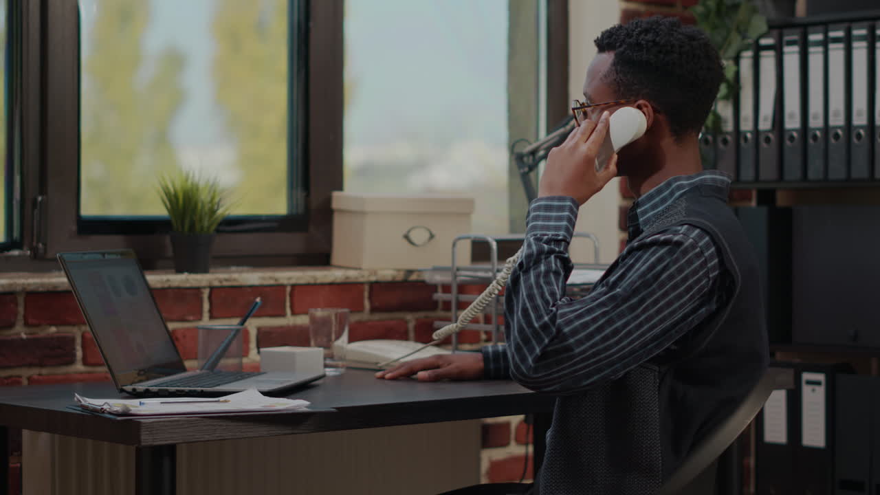 Office worker using landline phone to answer business call
