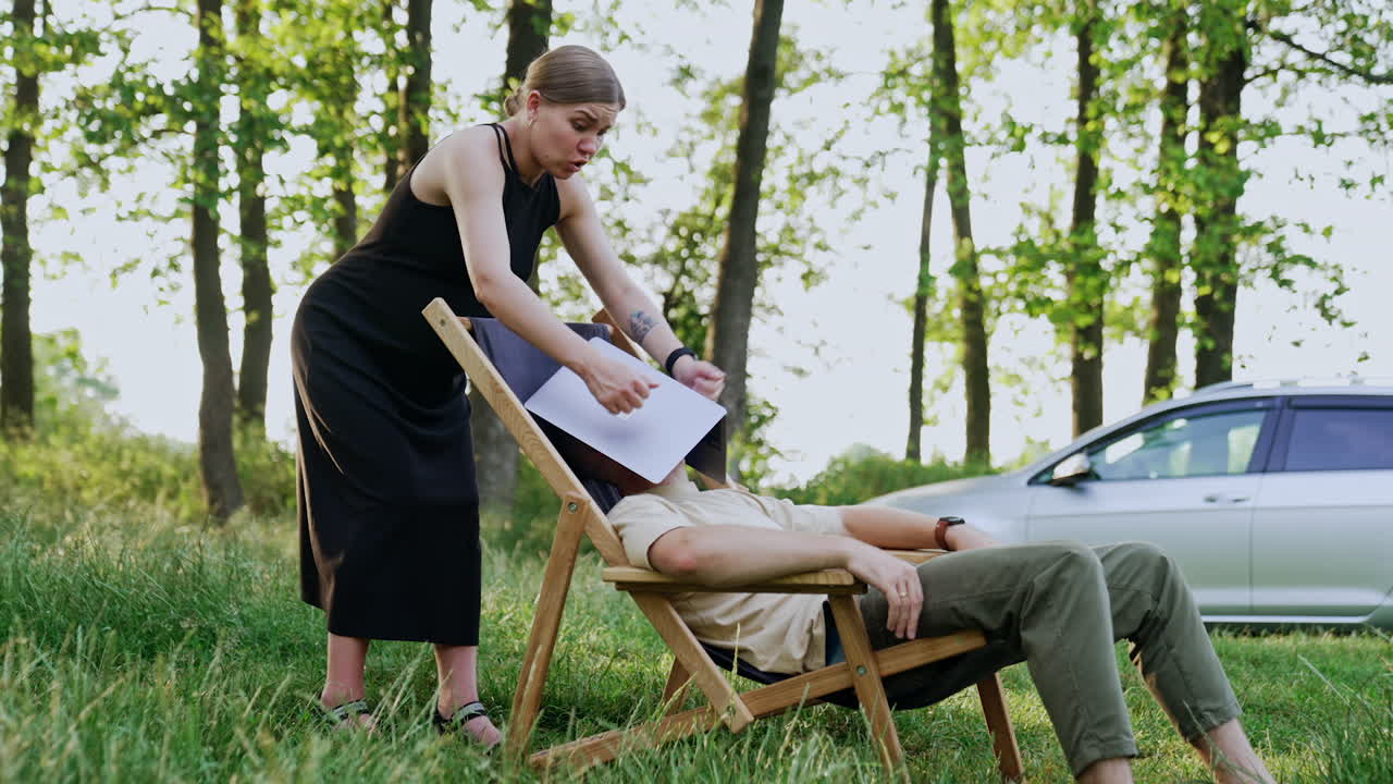Man working remotely in the nature took a break for a nap. Pregnant wife tells him off for laziness.