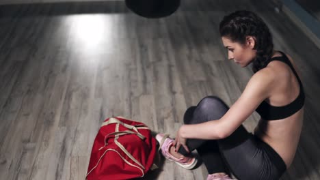 vista en primer plano de las piernas de la mujer caminando en un club de boxeo. joven boxeadora dejando su bolsa y sacando una botella con agua, guantes de boxeo y envolturas de boxeo preparándose para el entrenamiento. filmado en 4k