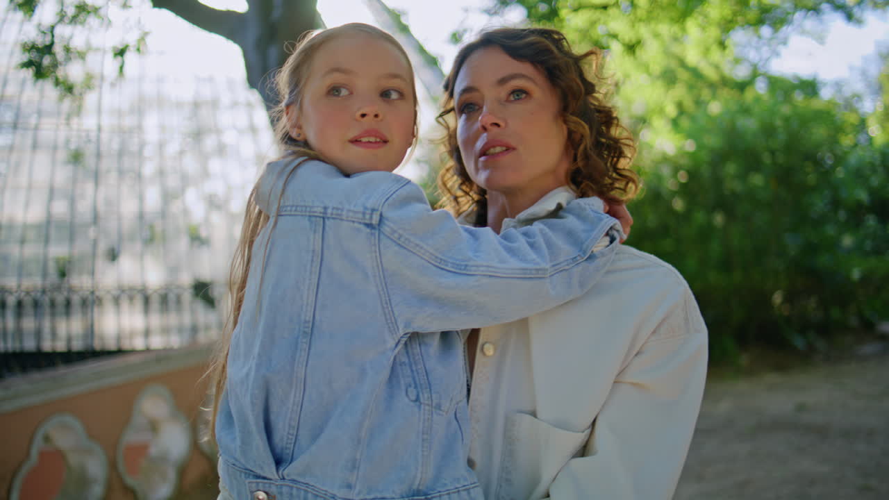 Loving mother carrying daughter walking on sunny park closeup. Family weekend