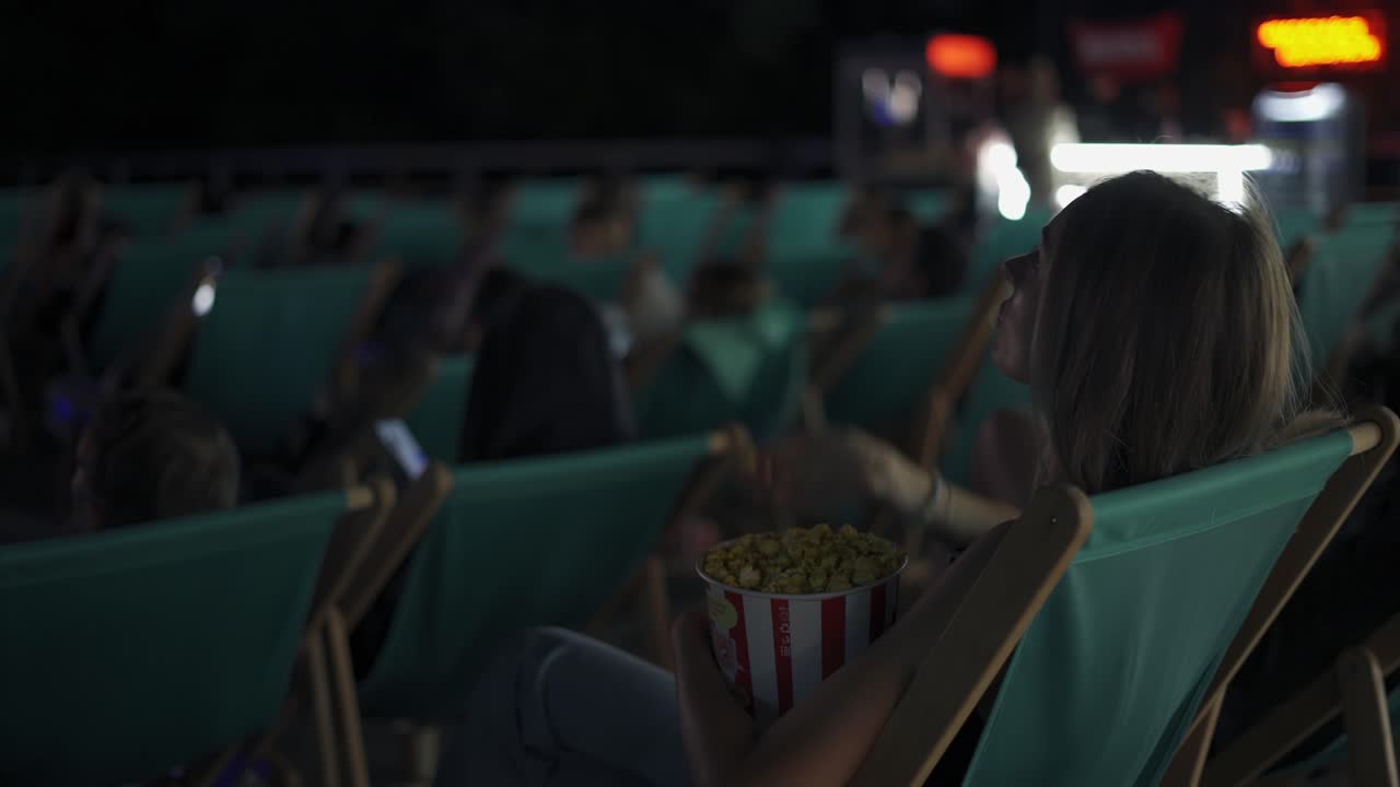 夏の映画館でポップコーンを食べている快適な椅子に座っている女性