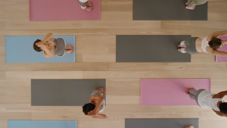 Vista-Superior-Clase-De-Yoga-Mujeres-Sanas-Practicando-Pose-De-Curvatura-Hacia-Adelante-Disfrutando-Del-Estilo-De-Vida-Físico-Haciendo-Ejercicio-En-El-Gimnasio