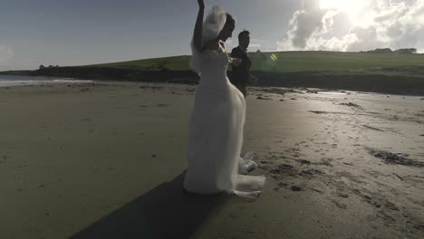 recién casados sonrientes bailando en la playa