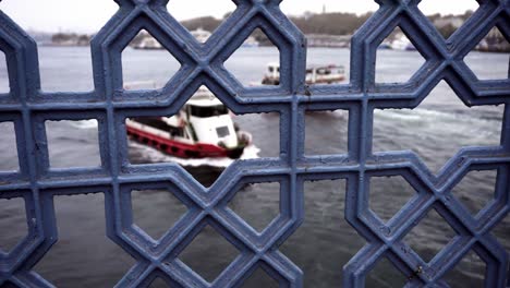 touristic boats passing by with istanbul in the background and fence in the foreground