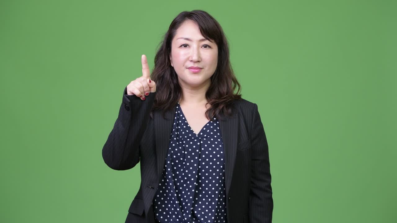 성숙하고 아름다운 아시아 사업가 여성이 손가락을 높이 가리키고 있습니다.