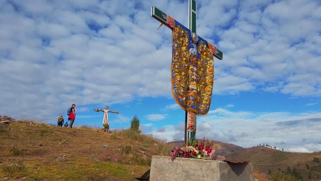 People trekking towards Wanakwari summit, ruins near Cusco, Peru. Tilt view looking at indigenous cross reveals cloudy sky