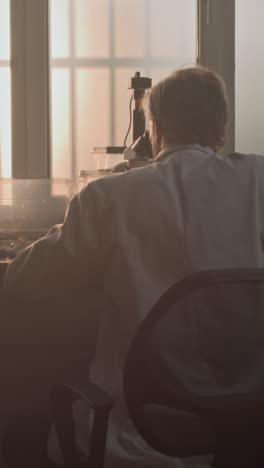 scientist in a laboratory, looking through a microscope.