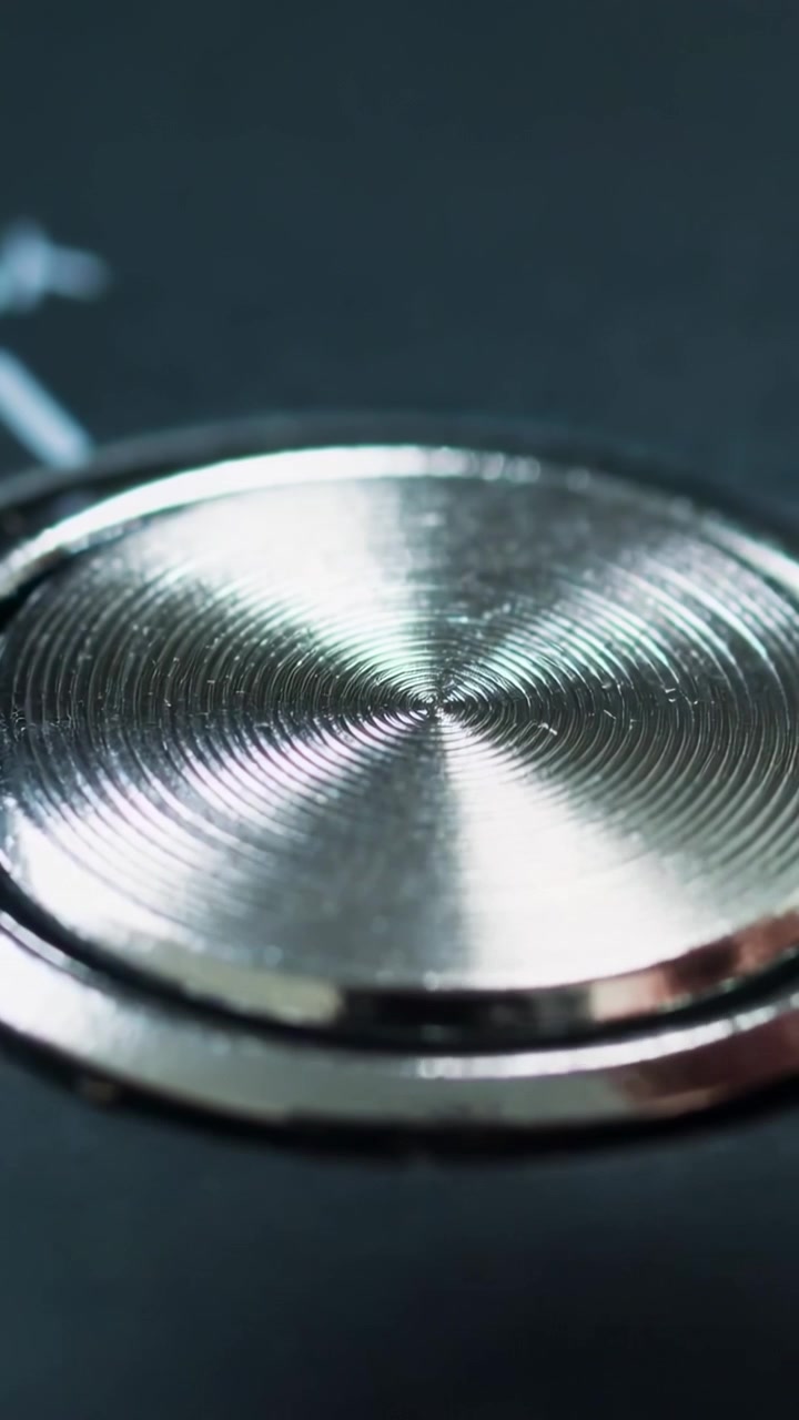 Vertical video: Entering right, fingertip pressing metal control on panel markings left, copy space