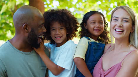 portrait of multi-racial family standing in garden smiling at camera