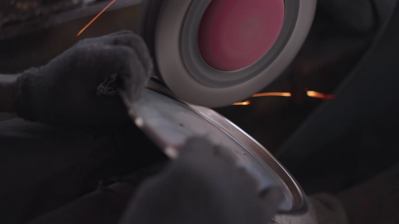 Using a belt sander to produce steel pan cookware in a factory