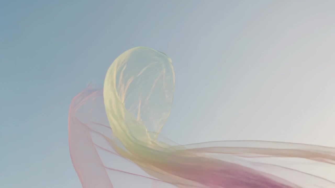 Lifting translucent fabric unfurling against clear blue sky by gentle breeze, pink yellow green