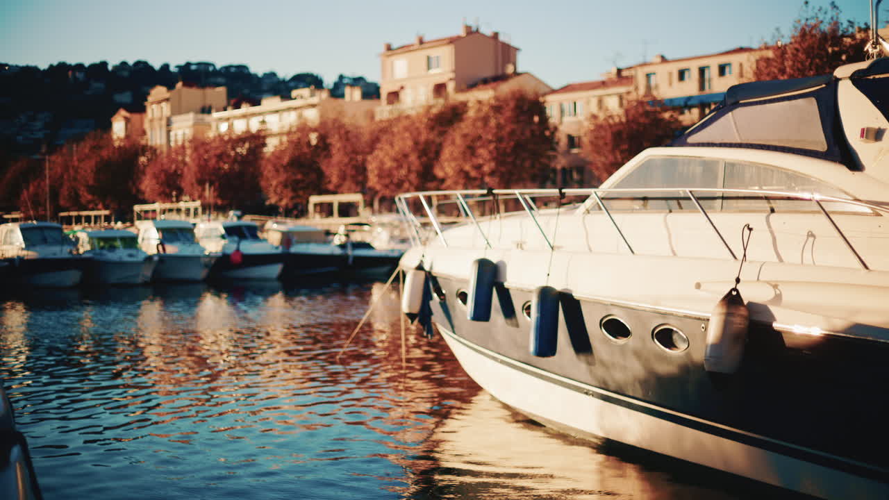 Yachts and sailing boats docked in a marina with sunlight reflecting on the water