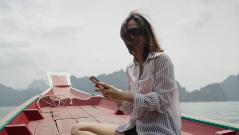 woman enjoying a boat trip on a scenic lake, looking at her phone