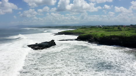 Aerial-drone-footage,-coastline-with-black-rocks-in-Bali