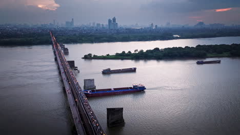 motorbike traffic over long bien bridge and ship passing under, twilight aerial