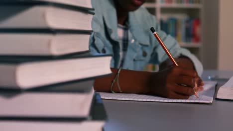 Close-up-of-book-stack-with-schoolboy-studying-in-background