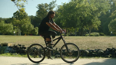 back view of man with artificial leg cycling along greenway