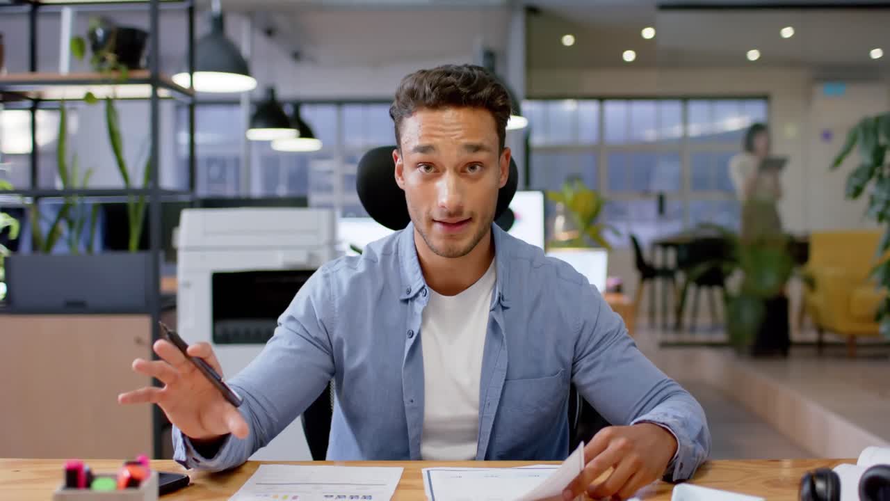 Biracial casual businessman talking during video call, working late at office, in slow motion
