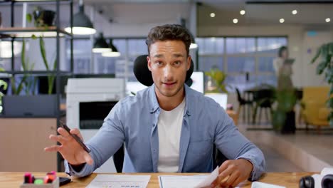 biracial casual businessman talking during video call, working late at office, in slow motion