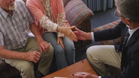 pareja de ancianos hablando con un hombre de negocios en una casa de jubilación