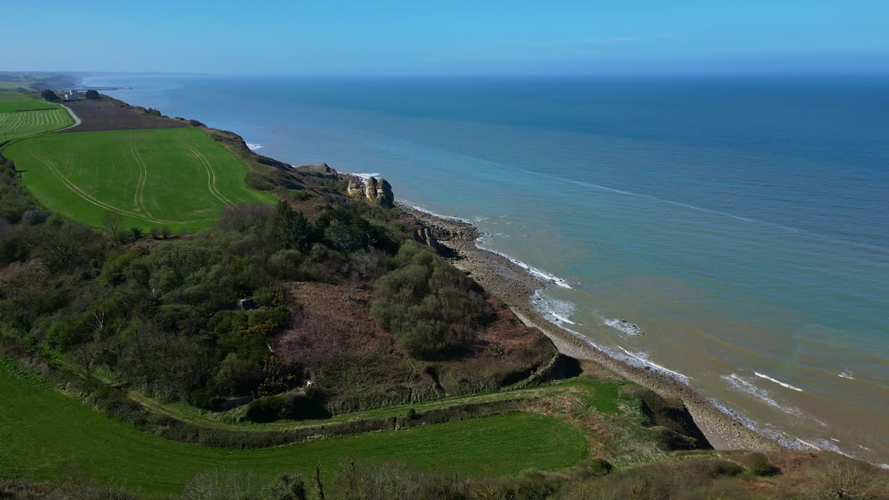 Rugged cliffs and coastline at Longues-sur-Mer, historic WWII German battery site in Normandy, France. Aerial drone panoramic view, seascape, copy space