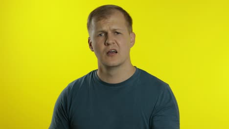 portrait of young man posing in green t-shirt. angry dissatisfied guy quarrels, waves his hands