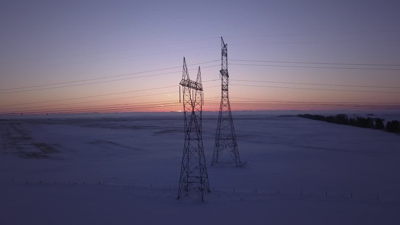 Aerial View of Power Lines at Sunset in a Snowy Landscape