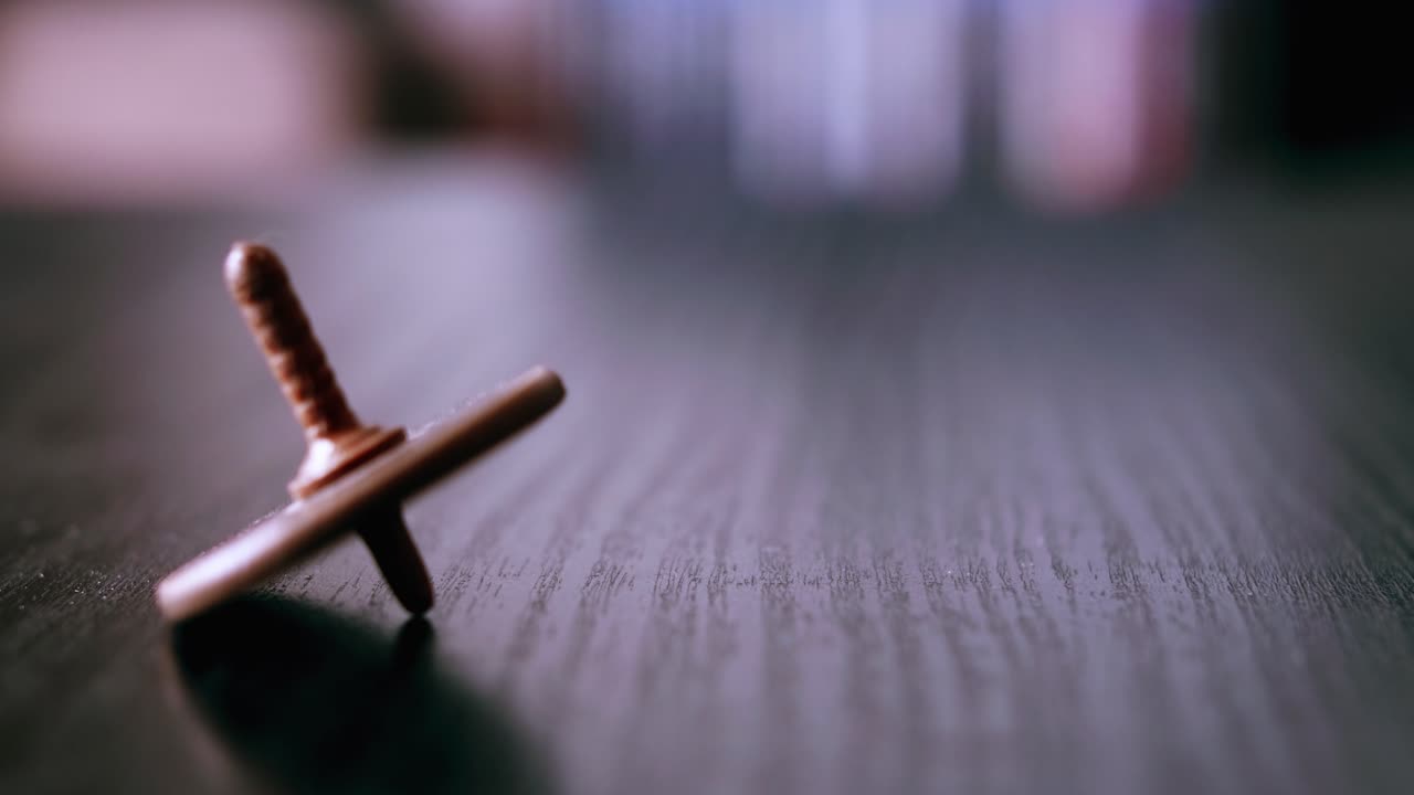 Primo piano di una trottola marrone che oscilla e cade