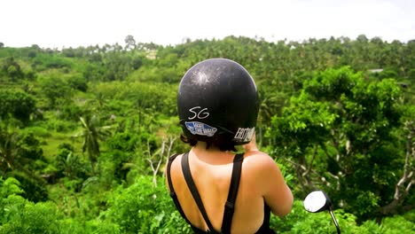 incredible shot of a girl in motorbike helmet taking a photo on the mountaintop