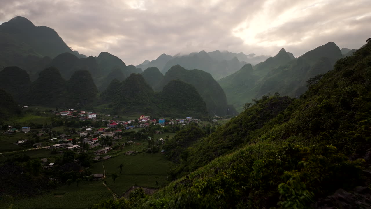 Male traveller on mountainside looks down on scenic Lung Ho village on Ha Giang