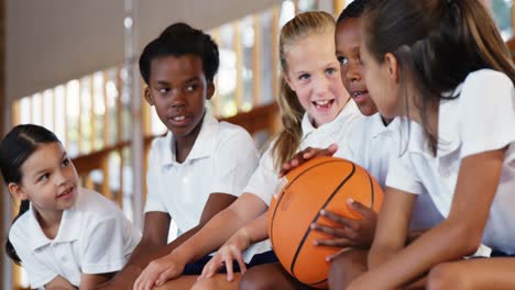 school kids sitting on bench in basketball court