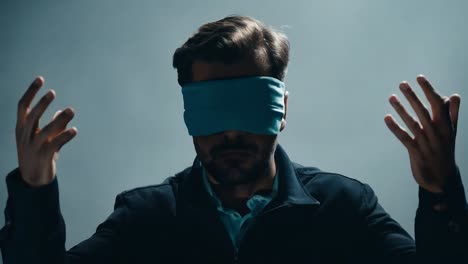 businessman wearing a blindfold raises his hands, expressing uncertainty and confusion in a studio setting