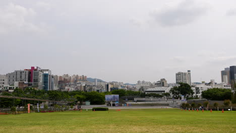 static wide shot of grass field park and skyline of gwangju city in background during cloudy day - south korea,asia